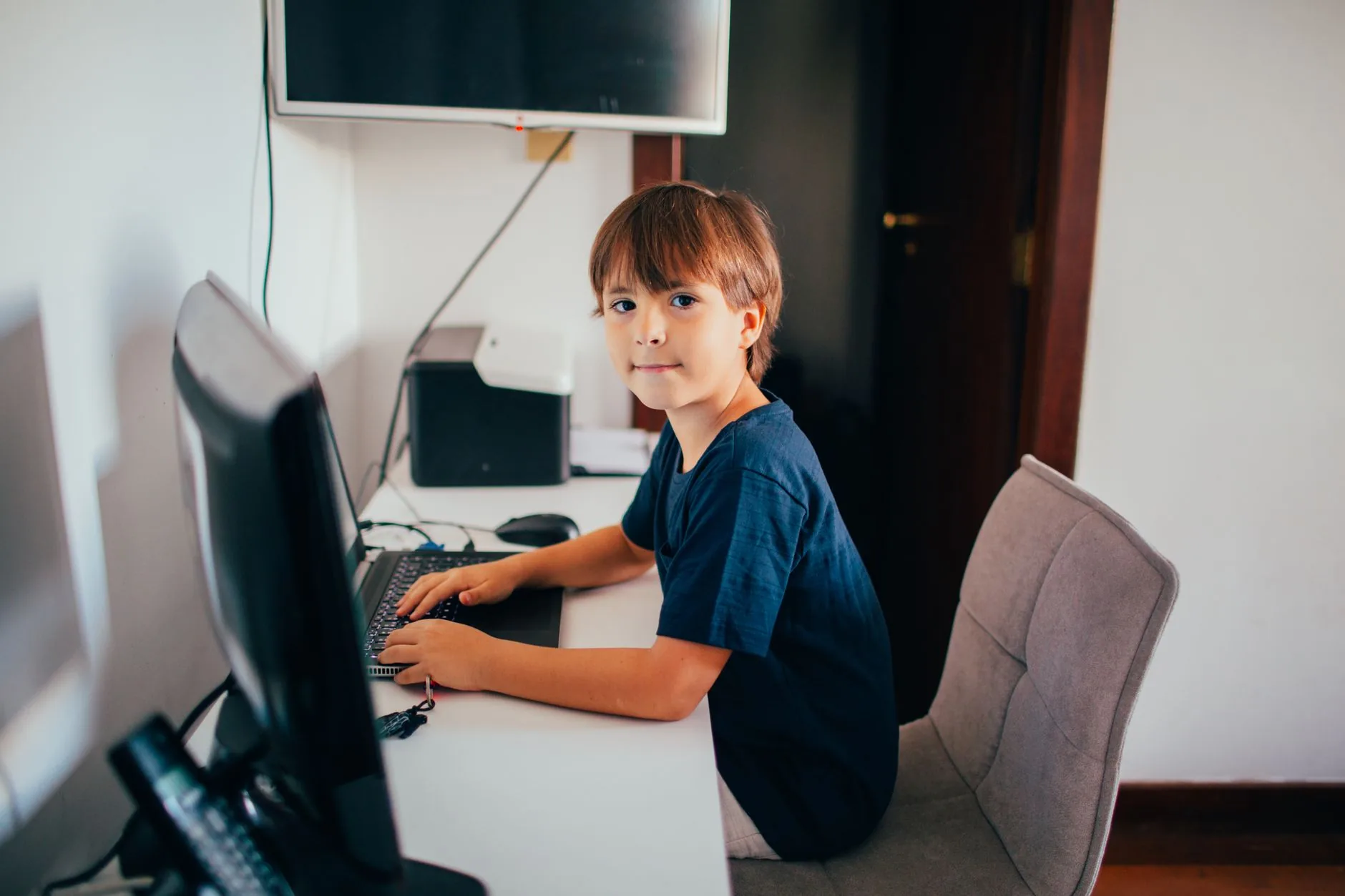 Jeune garçon concentré devant son ordinateur étudiant le dictionnaire informatique en ligne