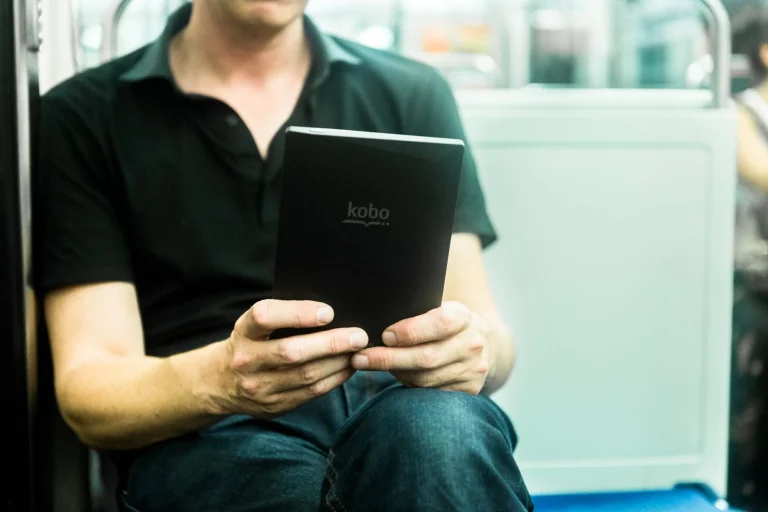 Homme lisant un ebook sur une liseuse électronique Kobo dans le métro parisien