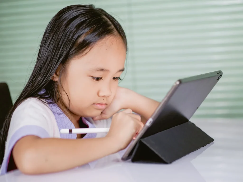 Jeune fille concentrée utilisant une tablette avec stylet pour un logiciel educatif en ligne