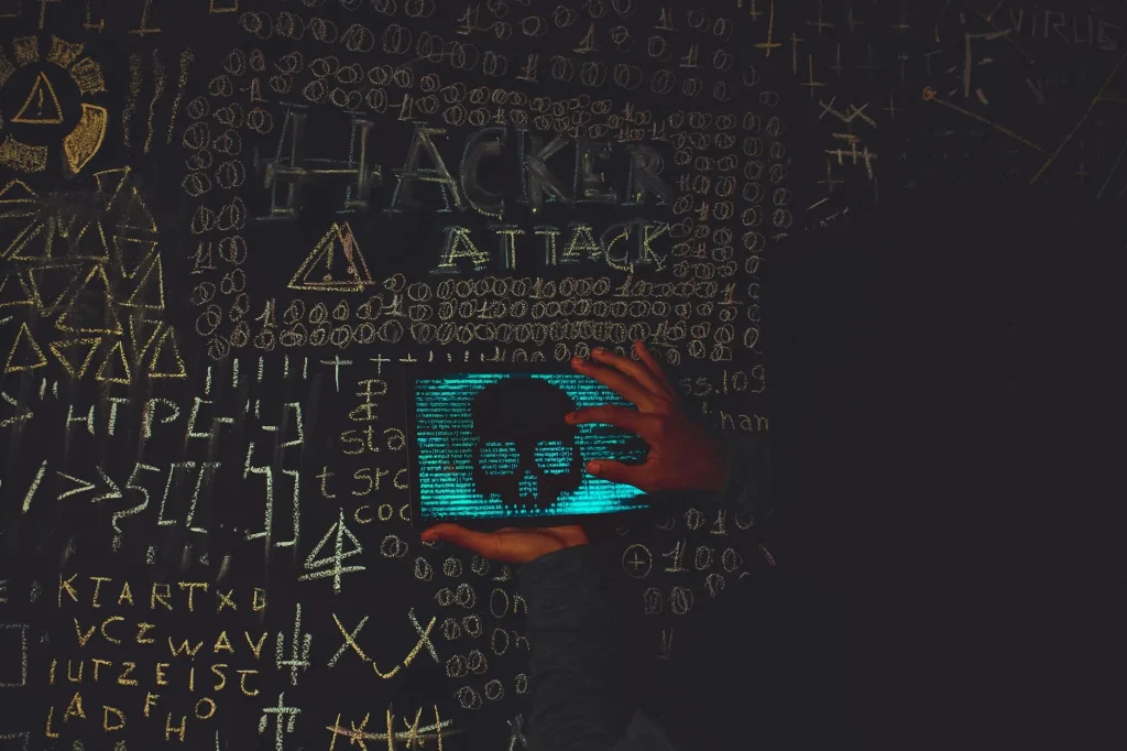 Hacker en hoodie noir utilisant une tablette affichant un crâne symbolisant une attaque virus informatique