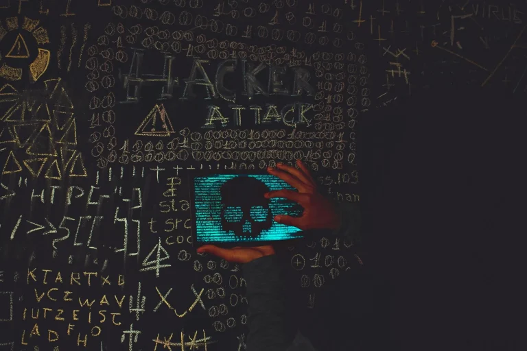 Hacker en hoodie noir utilisant une tablette affichant un crâne symbolisant une attaque virus informatique