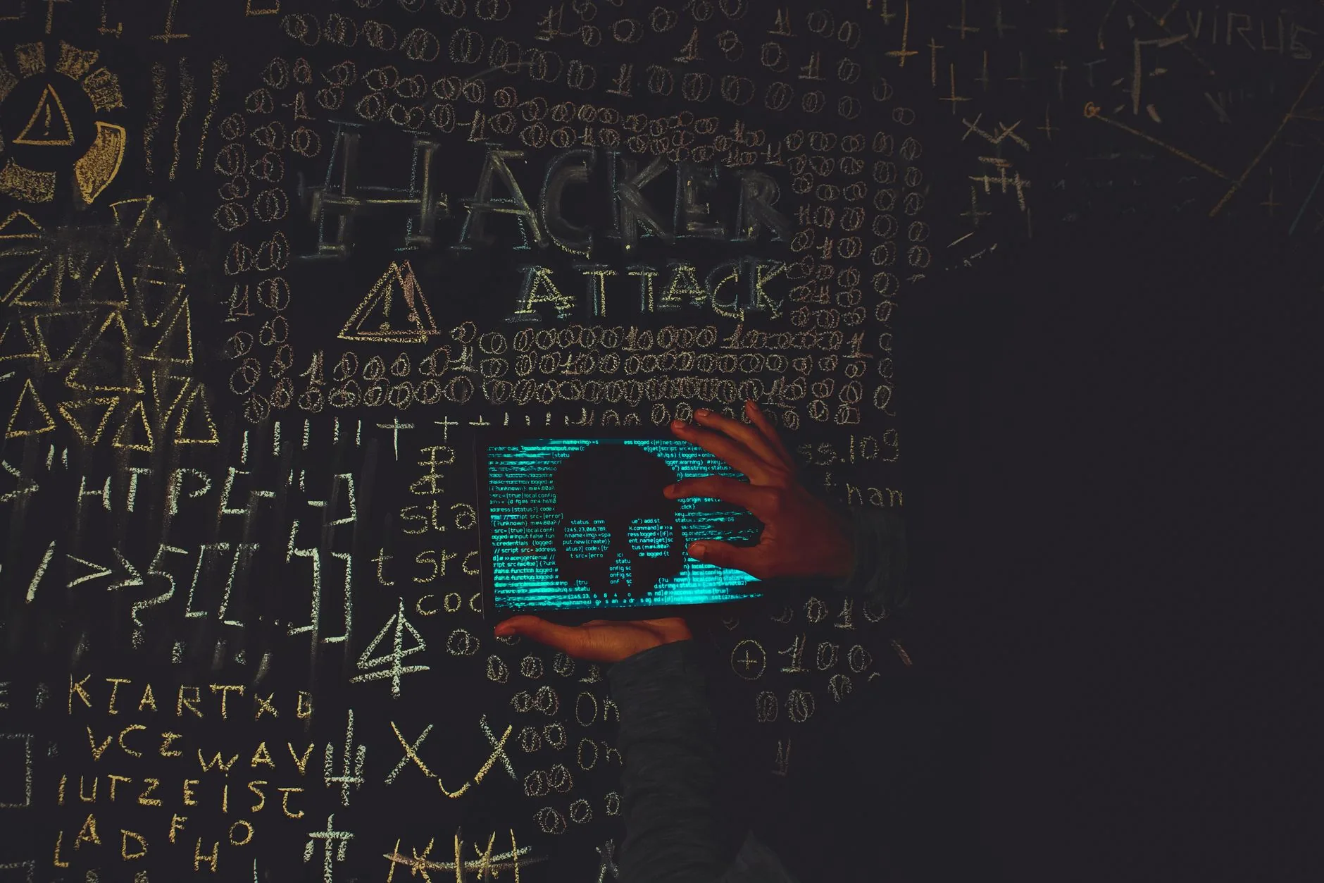 Hacker en hoodie noir utilisant une tablette affichant un crâne symbolisant une attaque virus informatique